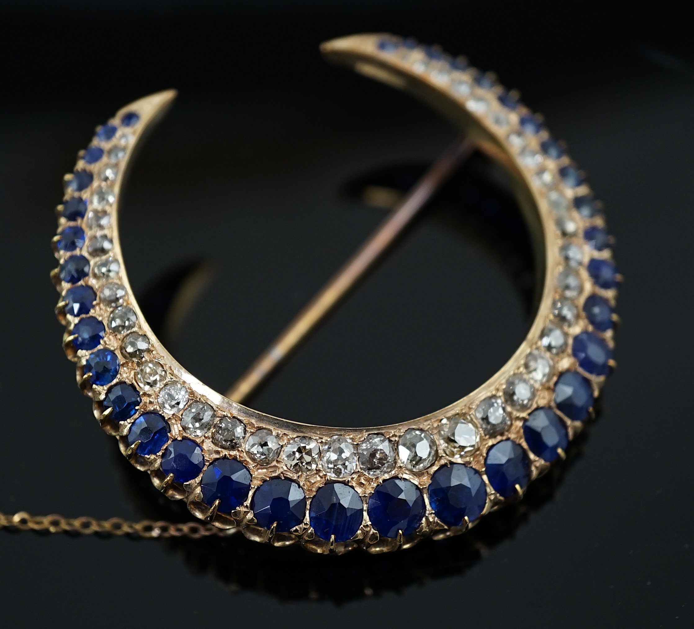An early to mid 20th century gold, graduated sapphire and graduated diamond set two row crescent brooch